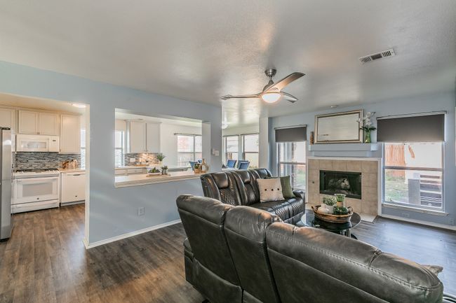 Living room with ceiling fan, dark wood-type flooring, and a tiled fireplace | Image 15