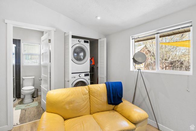 Sitting room with stacked washing maching and dryer, baseboards, vaulted ceiling, and wood finished floors | Image 25