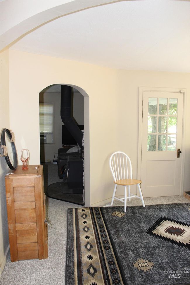 Dining space with arched walkways, carpet, and a wood stove | Image 6