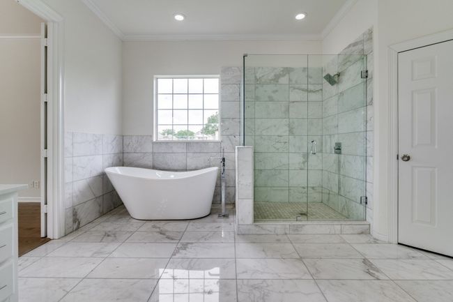 Bathroom with a freestanding tub, a stall shower, crown molding, recessed lighting, and tile walls | Image 16