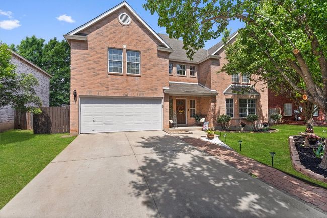 Traditional-style home featuring brick exterior and front covered porch. | Image 4