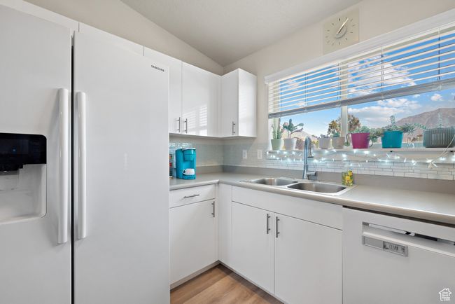 Kitchen featuring white appliances, decorative backsplash, light countertops, and lofted ceiling | Image 5