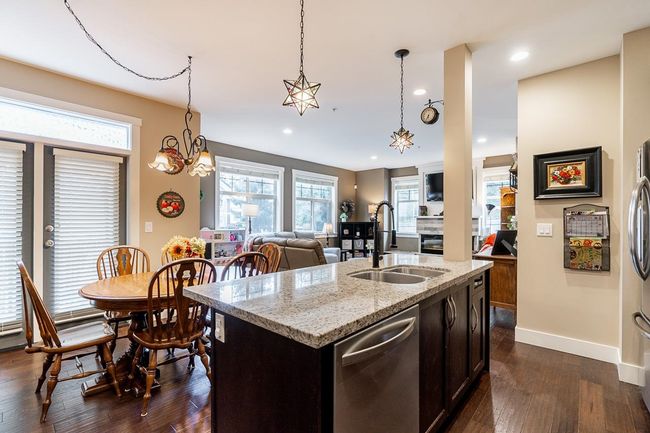 Kitchen with a sink, stainless steel appliances, dark wood finished floors, a kitchen island with sink, and baseboards | Image 7