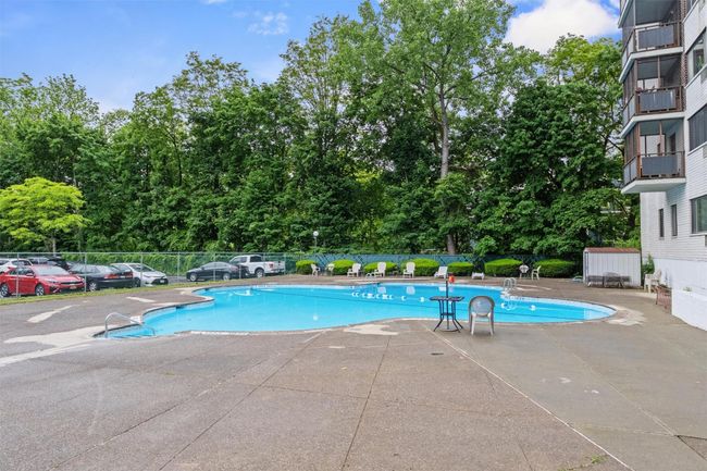Community pool with a patio area and view of wooded area | Image 18