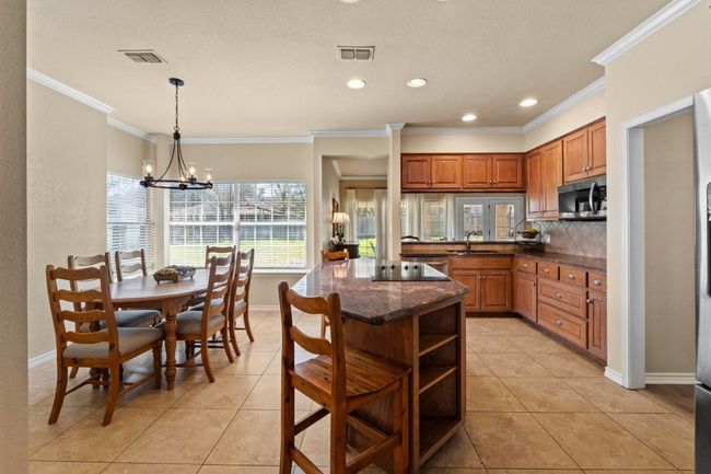 Kitchen with stainless steel microwave, visible vents, a sink, crown molding, and open shelves | Image 15