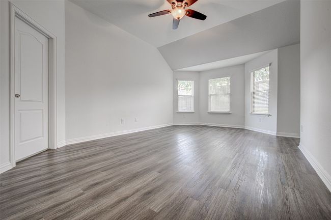 Spare room featuring a ceiling fan, dark wood-style flooring, and vaulted ceiling | Image 16