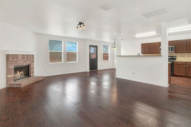 Unfurnished living room featuring dark wood-type flooring, baseboards, and a brick fireplace | Image 8