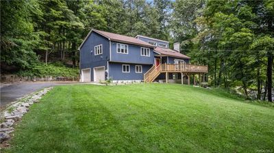 Back of house with a garage, a deck, and a lawn | Image 1