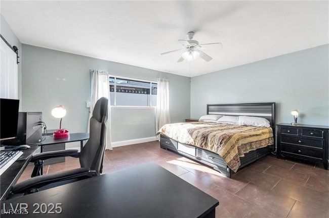 Tiled bedroom with an office area, a barn door, baseboards, and ceiling fan | Image 16