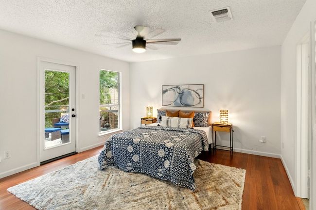 private primary suite is a true retreat with balcony access overlooking the backyard, refinished hardwood floors, and a luxurious en-suite bath. | Image 13