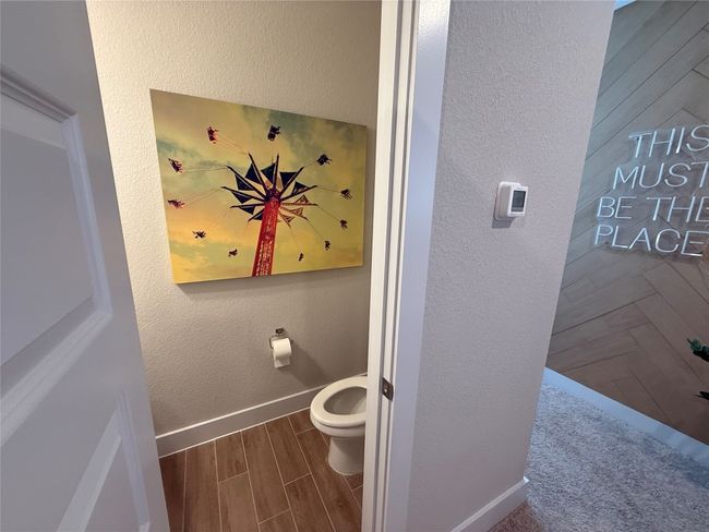 Bathroom featuring toilet, wood finished floors, baseboards, and a textured wall | Image 19
