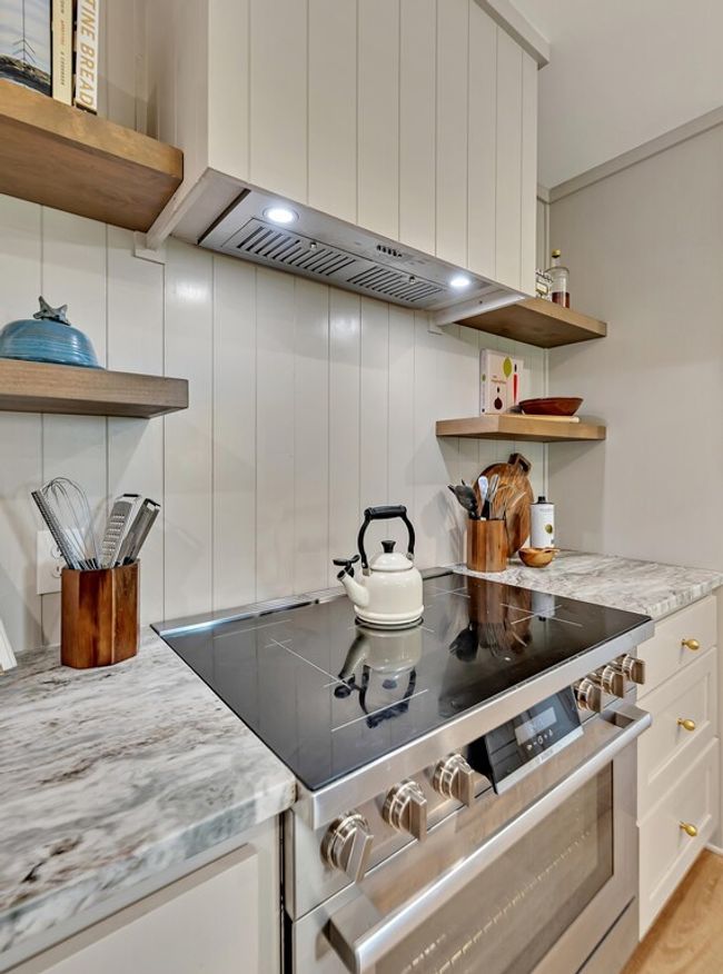 Kitchen with open shelves, stainless steel electric range, white cabinetry, granite counters, and custom exhaust hood | Image 14