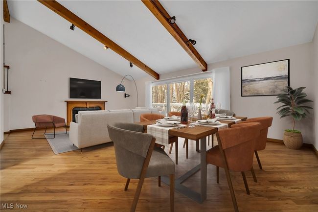 Virtually staged great room has hardwood floors, vaulted beamed ceiling, decorative fireplace, triple sliding doors to deck overlooking wood backyard | Image 10
