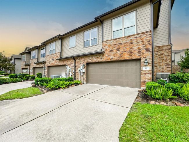 This photo showcases a modern townhouse with a brick facade and attached two-car garage. The property features well-maintained landscaping and a spacious driveway, set in a tidy, suburban neighborhood. | Image 36