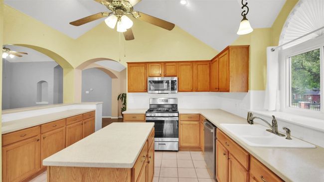 Kitchen with appliances with stainless steel finishes, ceiling fan, light countertops, decorative light fixtures, and light tile patterned floors | Image 17