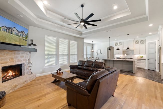 Living area featuring a fireplace, a raised ceiling, a ceiling fan, and recessed lighting | Image 5