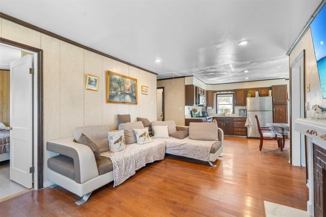 Living room with light wood-type flooring, recessed lighting, crown molding, and wood walls | Image 14