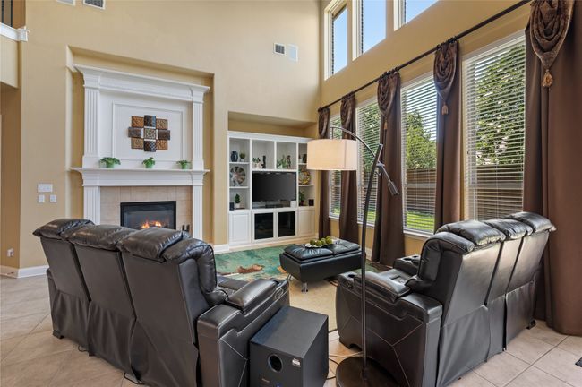 Living area with light tile patterned floors, a towering ceiling, and a tiled fireplace | Image 11