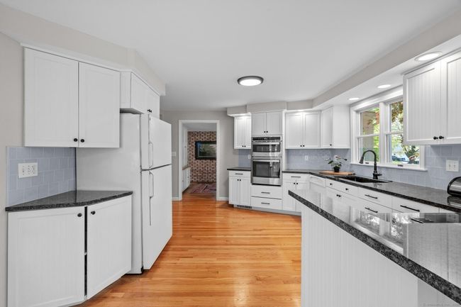 Perfectly detailed with granite, custom cabinets, recessed lighting, and pretty hardwood floors. | Image 7