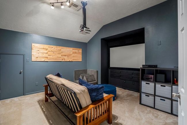 The media room is ready for movie marathons, featuring a unique recessed area perfectly designed for a movie screen, ensuring optimal viewing from every angle. A small door to the left provides convenient access to attic space, adding extra storage or organization options. | Image 26