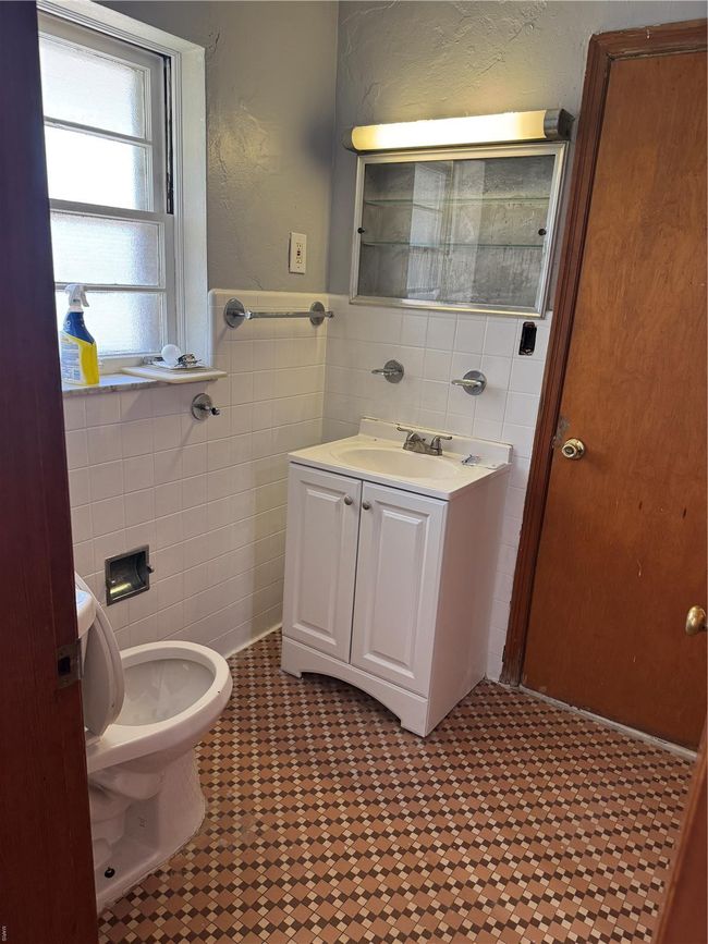 Bathroom featuring toilet, vanity, and tile walls | Image 6