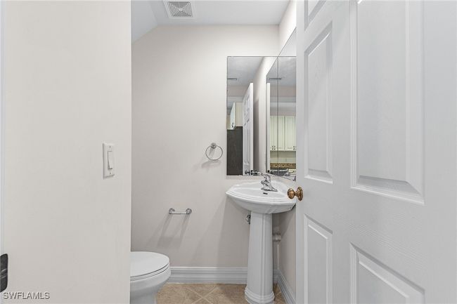 Half bathroom with toilet and tile patterned floors | Image 9