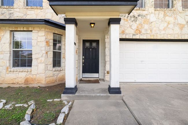 View of exterior entry with stone siding, a garage, and driveway | Image 12