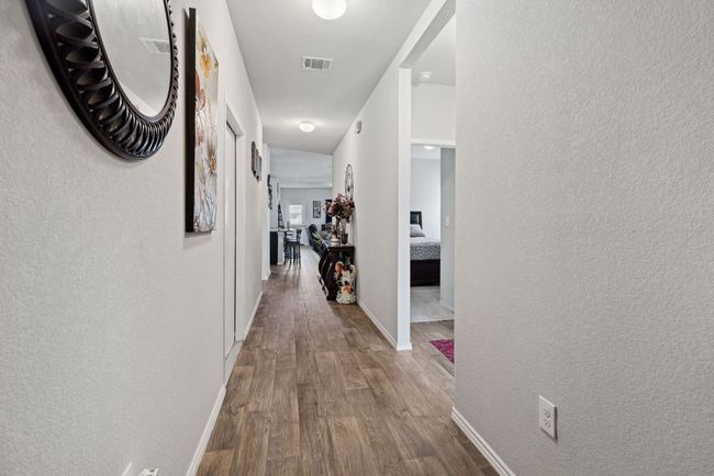 Hallway featuring wood-vinyl finished floors, a textured wall, and baseboards | Image 6