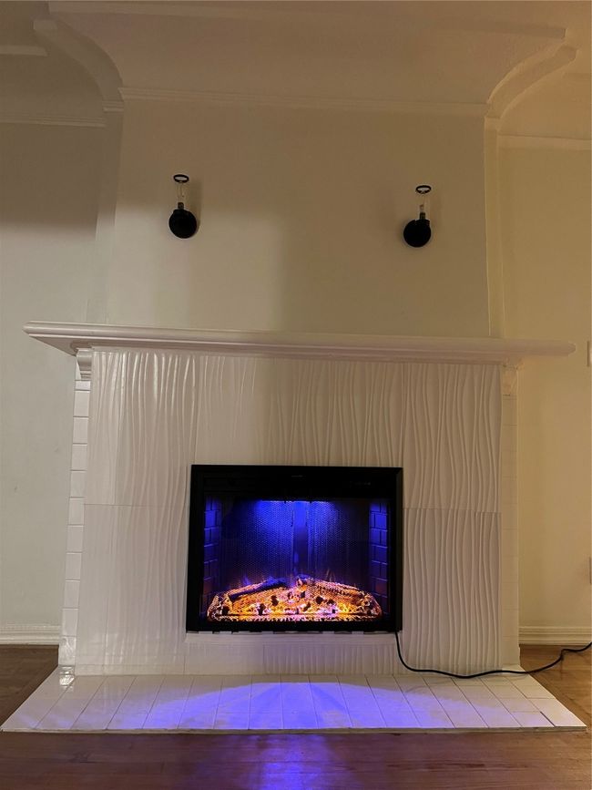Detailed view of a warm lit fireplace, wood finished floors, and baseboards | Image 9