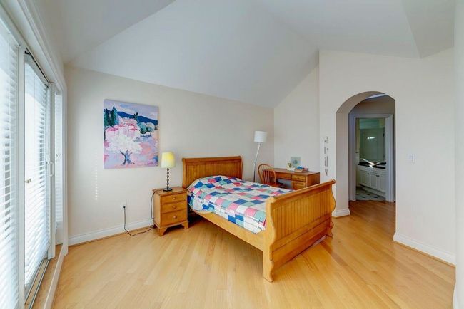Bedroom with light wood-type flooring, arched walkways, lofted ceiling, and baseboards | Image 7