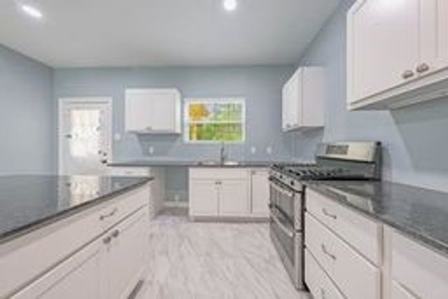Kitchen featuring white cabinets, a sink, dark countertops, and range with two ovens | Image 16