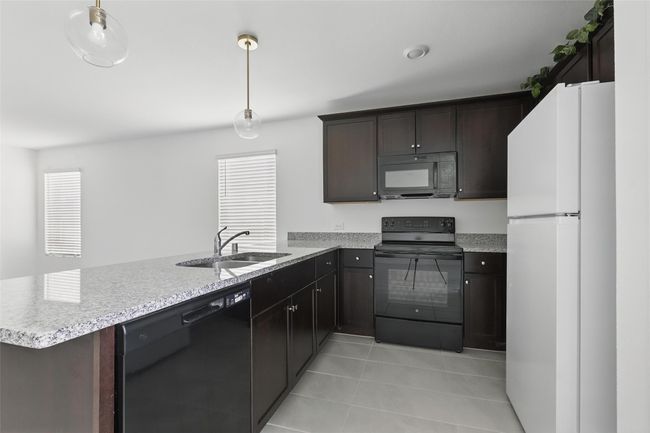 Kitchen featuring a peninsula, a wealth of natural light, a sink, and black appliances | Image 4