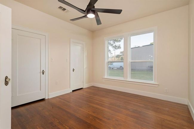 In this secondary bedroom, you'll appreciate the restored hardwood original floors, large windows, high ceiling with a modern fan with light kit, and dual closets. | Image 28