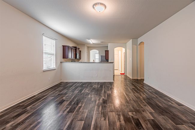Unfurnished living room featuring arched walkways, dark wood-style flooring, and baseboards | Image 16