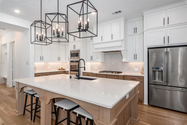 Dream kitchen with oversized island, single-basin blanco sink, white cabinetry, gas cooktop, undercabinet lighting and more | Image 15