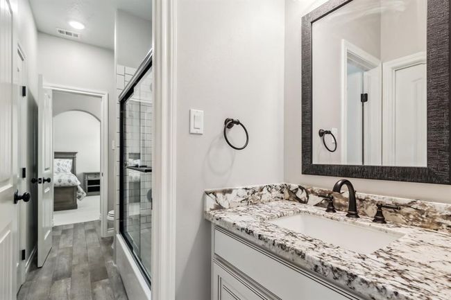 The upstairs secondary bedrooms share a well-appointed Hollywood bath, complete with granite counters and a functional tub/shower combo. | Image 31
