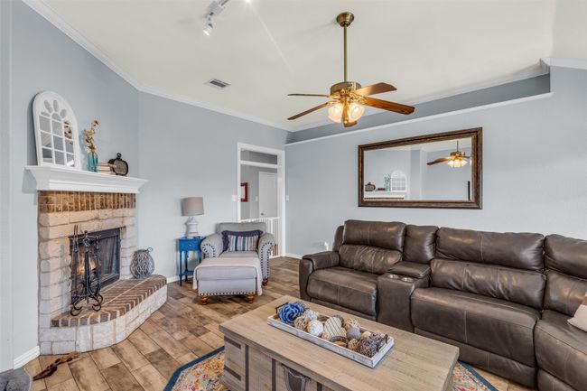 Living room featuring a fireplace, track lighting, ornamental molding, ceiling fan, and hardwood / wood-style flooring | Image 16