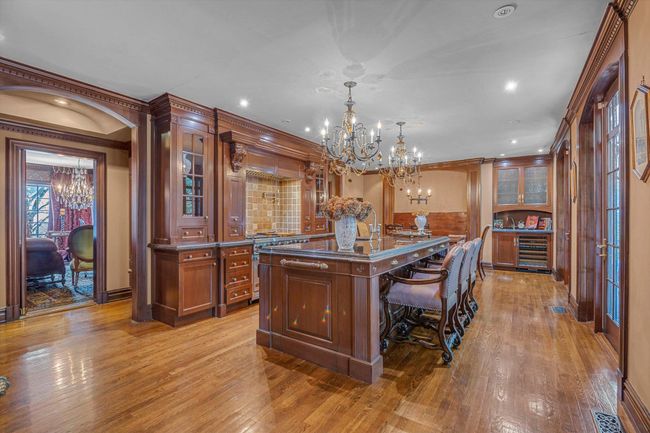Kitchen with pendant lighting, stainless steel stove, a breakfast bar area, a center island, and light hardwood / wood-style floors | Image 6