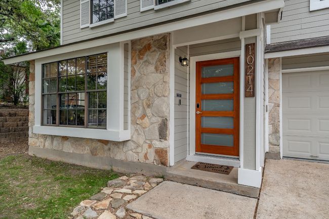 Doorway to property featuring stone siding and a garage | Image 5