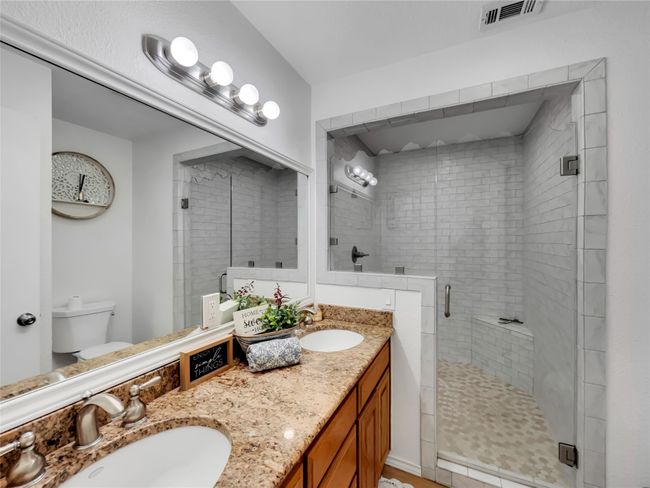 Bathroom featuring double vanity, toilet, and a stall shower | Image 4