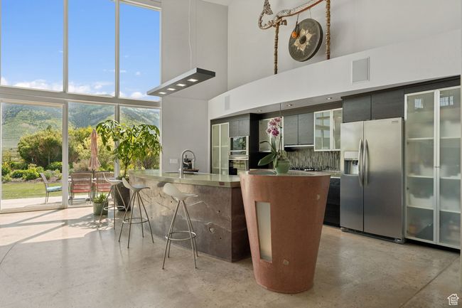 Kitchen with stainless steel appliances, a towering ceiling, backsplash, a sink, and a breakfast bar | Image 11