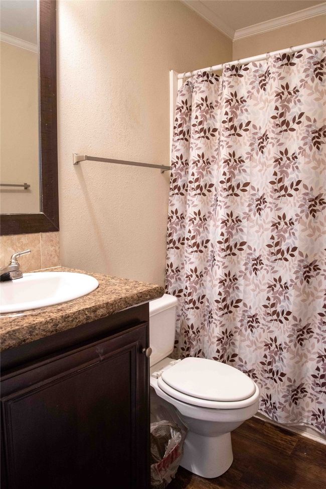 Guest bathroom with crown molding, vanity, toilet, curtained shower, and wood finished floors | Image 35