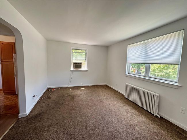 Spare room with radiator, carpet, arched walkways, and cooling unit | Image 4