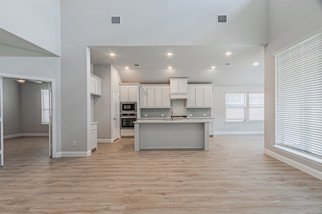 Kitchen with stainless steel oven, black microwave, white cabinetry, a high ceiling, and light countertops | Image 13