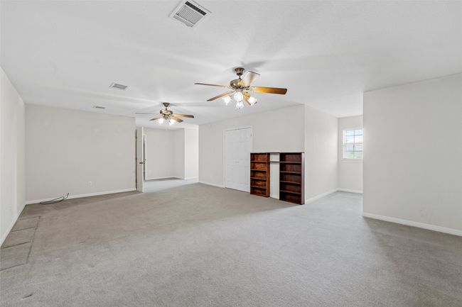 Unfurnished living room with carpet floors, visible vents, baseboards, and ceiling fan | Image 13