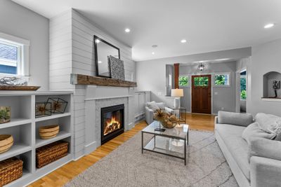 Cozy up in the inviting living room, featuring a gas-burning fireplace adorned with marble tile and shiplap surround, complemented by a reclaimed wood mantle and built-in cabinetry. | Image 3