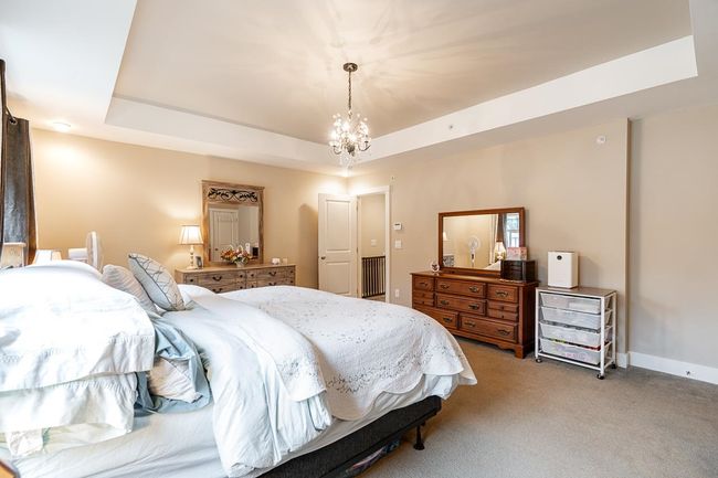 Bedroom featuring a tray ceiling, light carpet, a chandelier, and baseboards | Image 18
