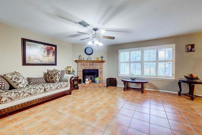 Living room with a ceiling fan, light tile patterned floors, a brick fireplace, and a textured ceiling | Image 8