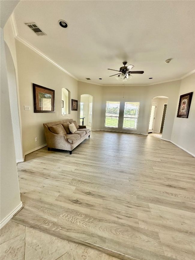 Living area featuring ceiling fan, ornamental molding, light wood-type flooring, and arched walkways | Image 5