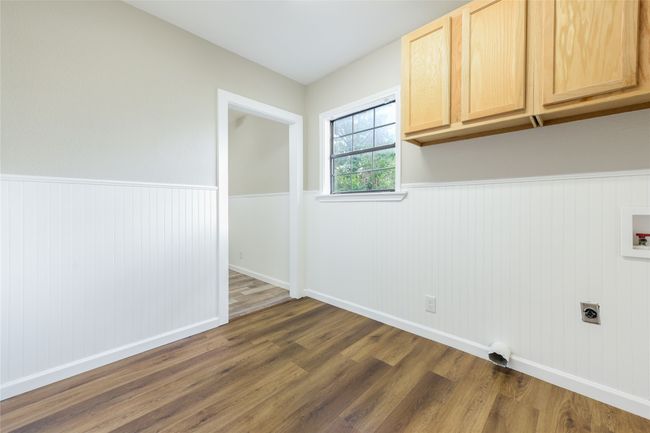 Washroom featuring cabinet space, hookup for an electric dryer, dark wood finished floors, wainscoting, and hookup for a washing machine | Image 38